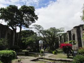 Trees, flower bushes and stone pathways grace the inside of the ruins.